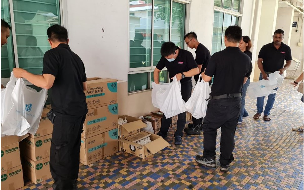 A group of people unpack cardboard boxes and white plastic bags in an apartment complex