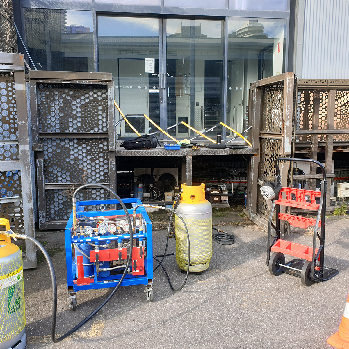 Two grey recovery cylinders attached to a blue unit on a site on-site