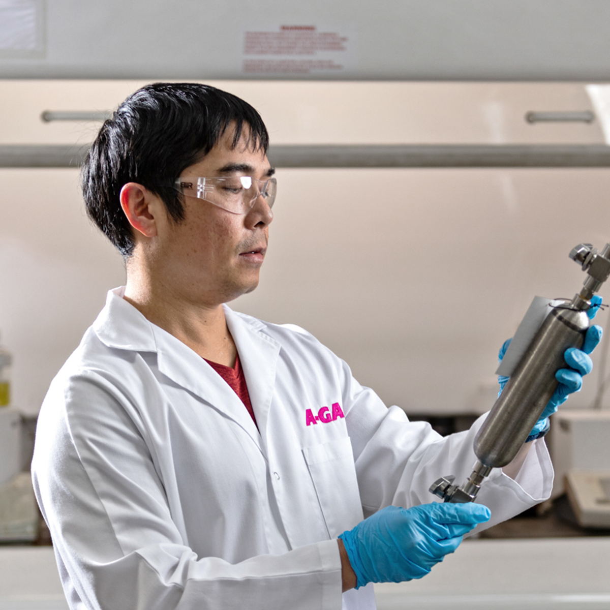 Technician in a white coat holding a silver metal tool in a laboratory