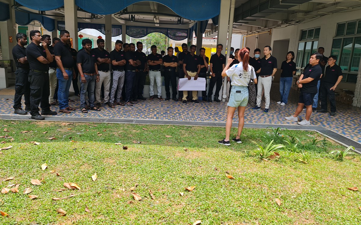 A woman speaks to a group of people in an outside area