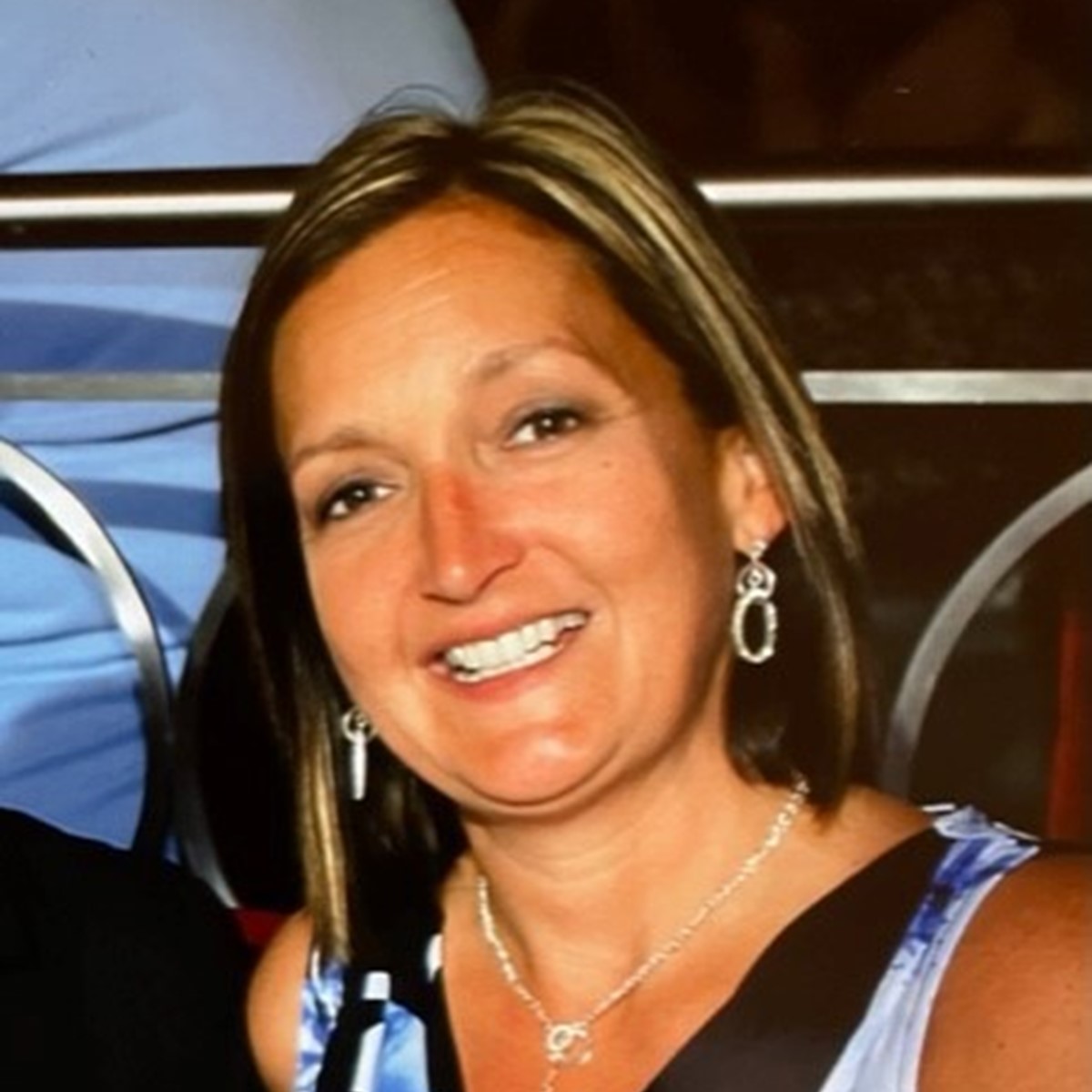 A close-up of a woman smiling at the camera with a dark background