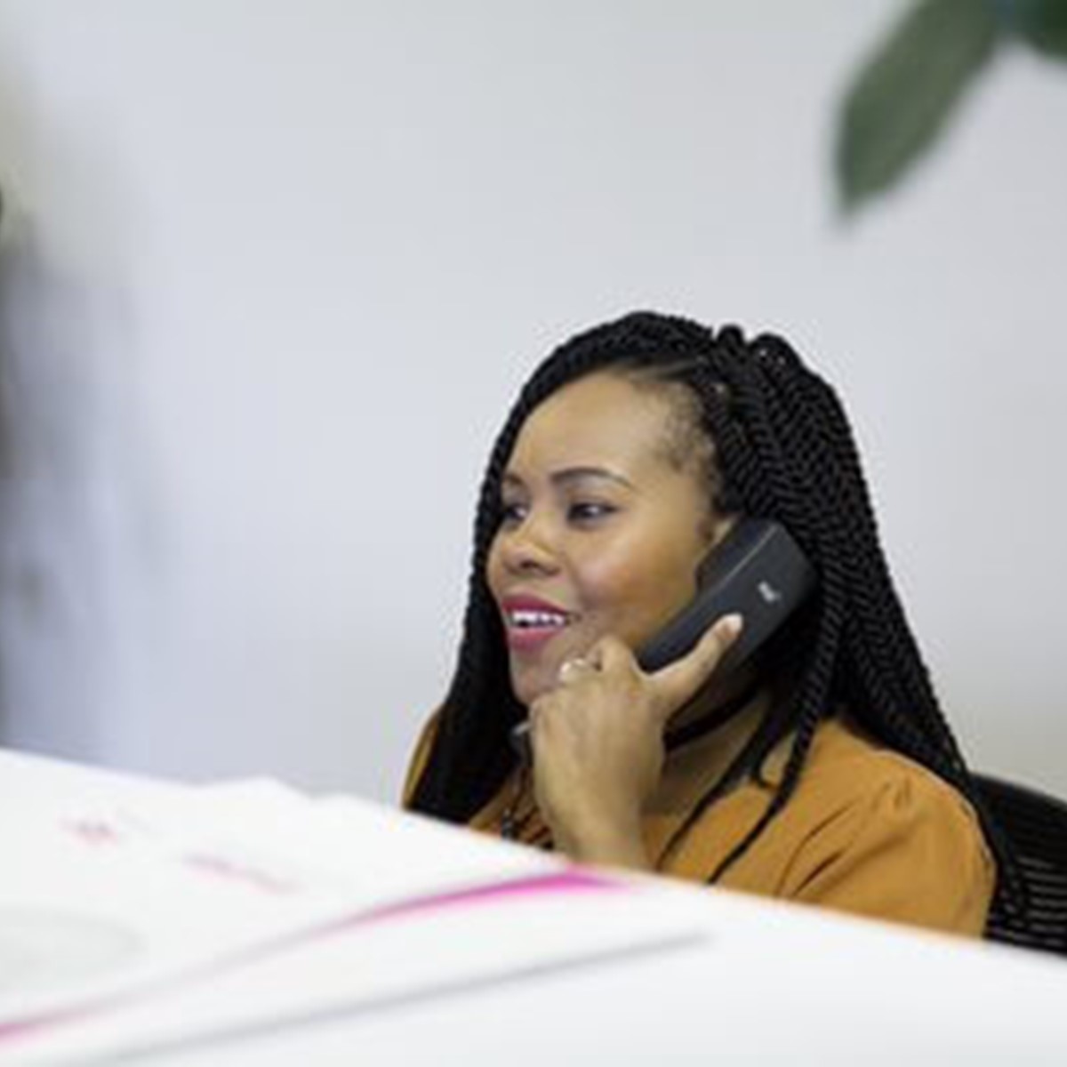 A woman sat at a desk using the phone