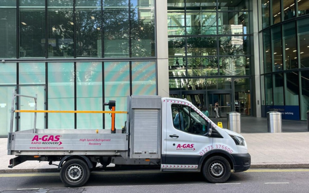 A white truck with the pink A-Gas logo on the side parked outside a green office building
