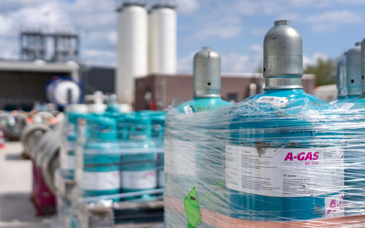 Blue cylinders wrapped in clear plastic on palettes outside