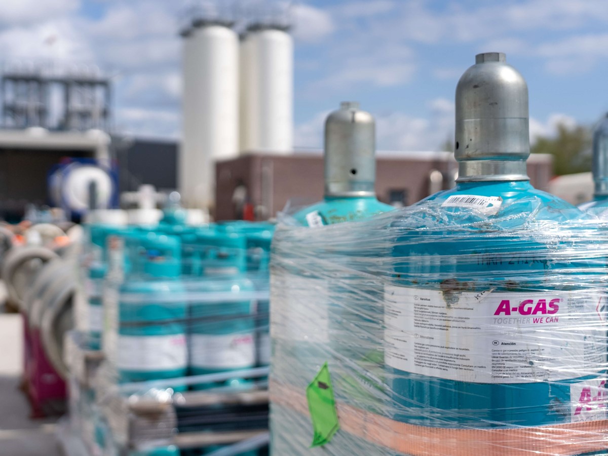 Blue cylinders wrapped in clear plastic on palettes outside