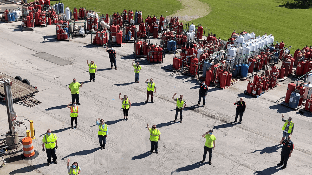 Workers lined up on site waving to the drone taking the photo