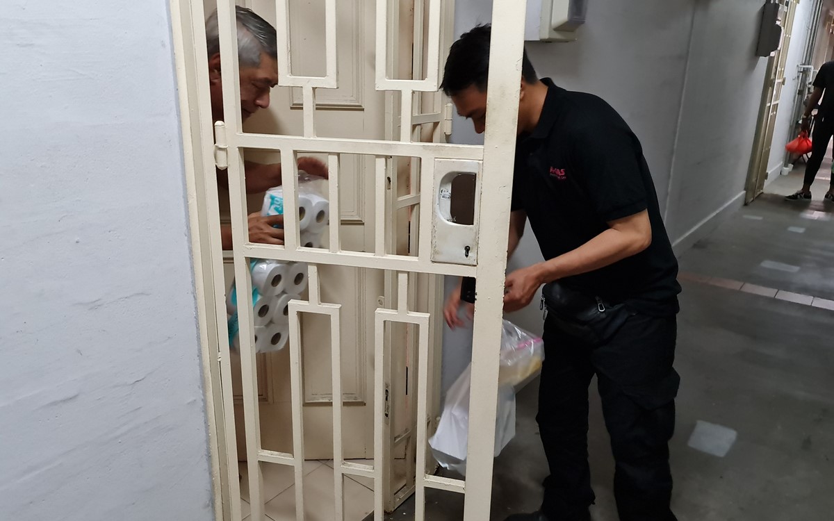 A man hands another man some toiletries and goods through a doorway