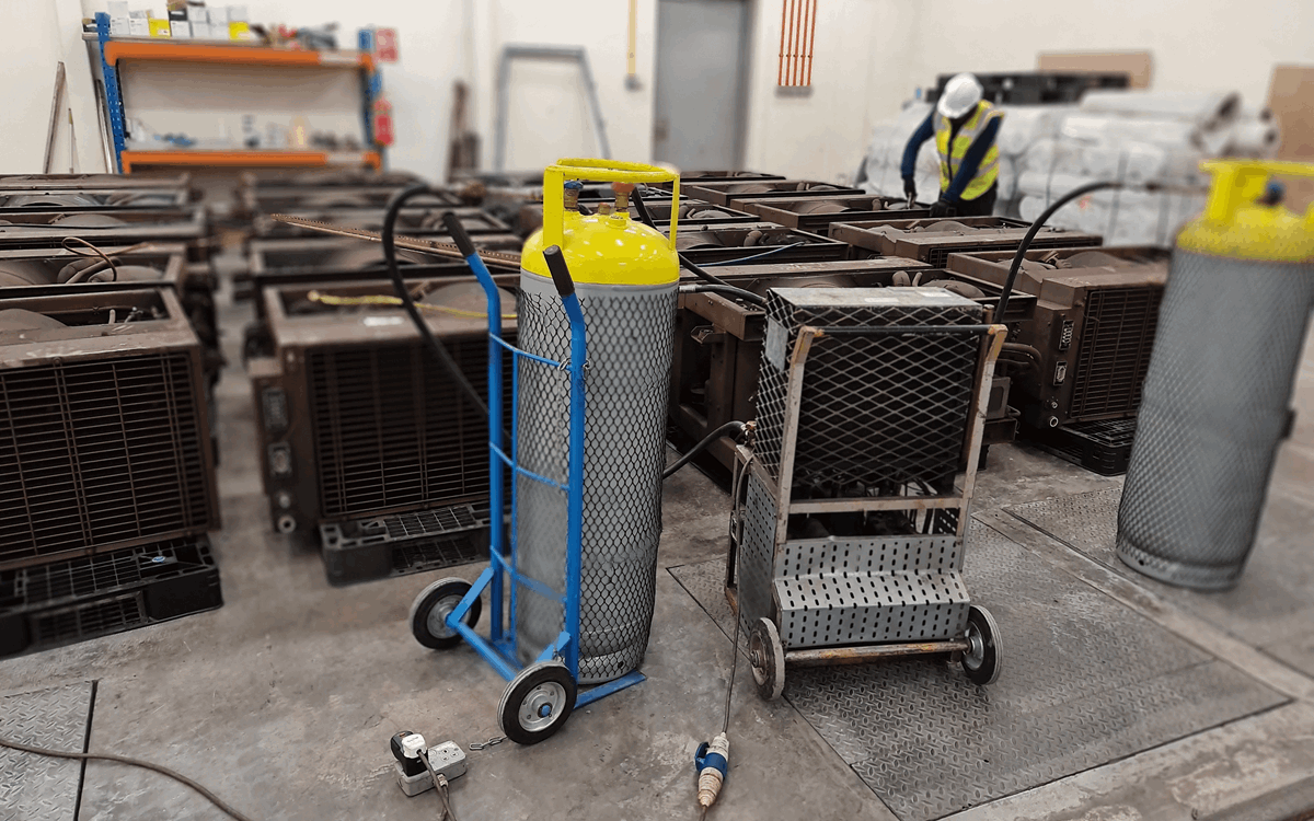 Two large grey recovery cylinders being used with large air conditioning units in a warehouse