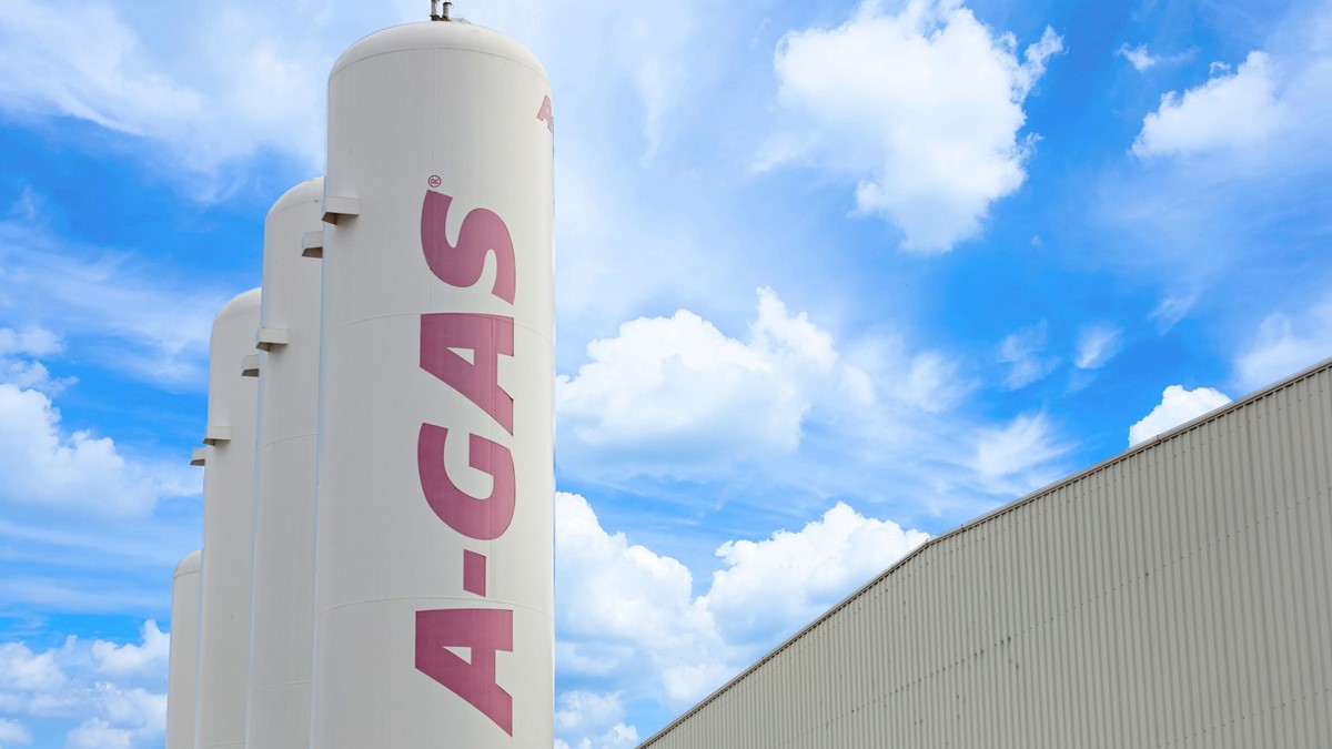 Three white separation towers with pink A-Gas logo outside a building