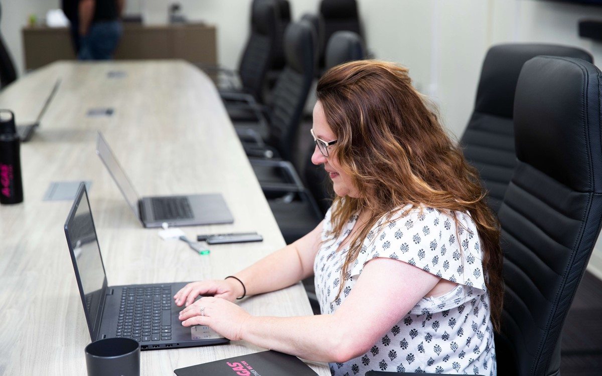 A close up of a woman sat in the boardroom working on her laptop