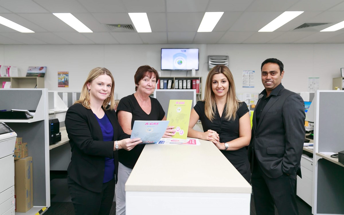 four workers in office environment looking at camera and smiling