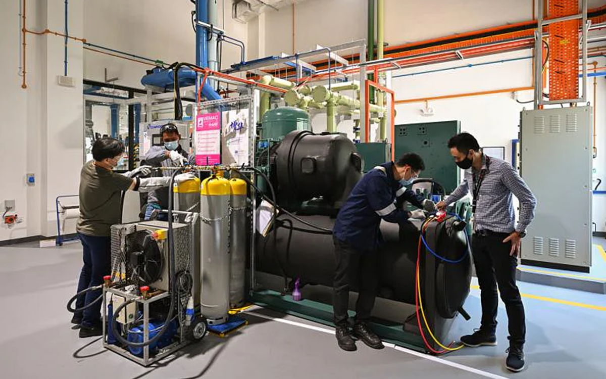 Three men working with gas recovery equipment in a warehouse