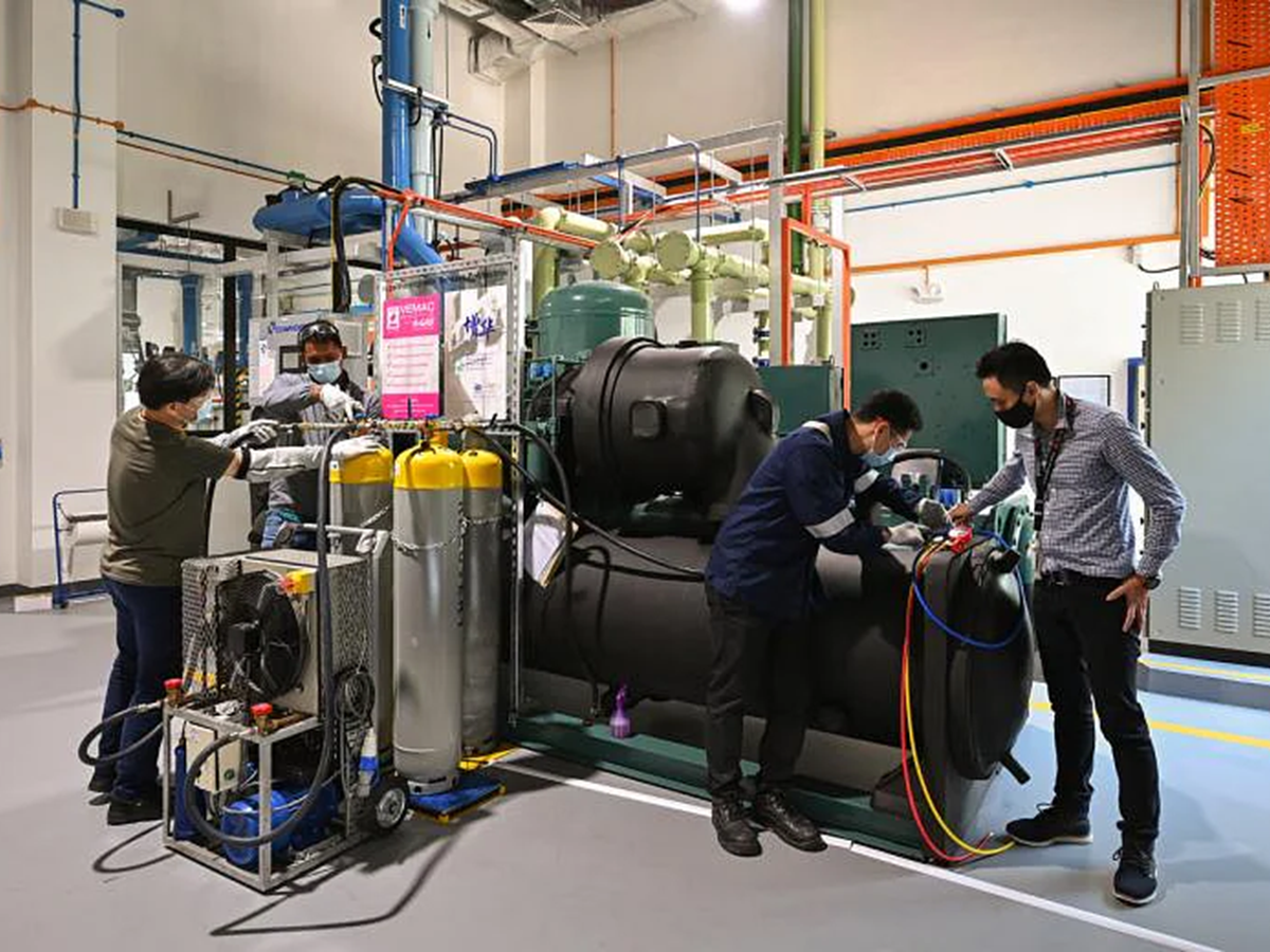 Three men working with gas recovery equipment in a warehouse