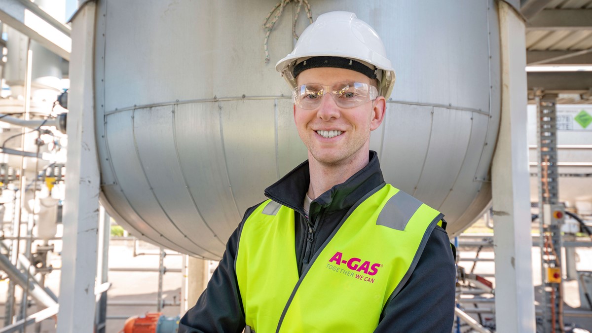 A man in a yellow high-vis jacket and safety helmet smiling at the camera