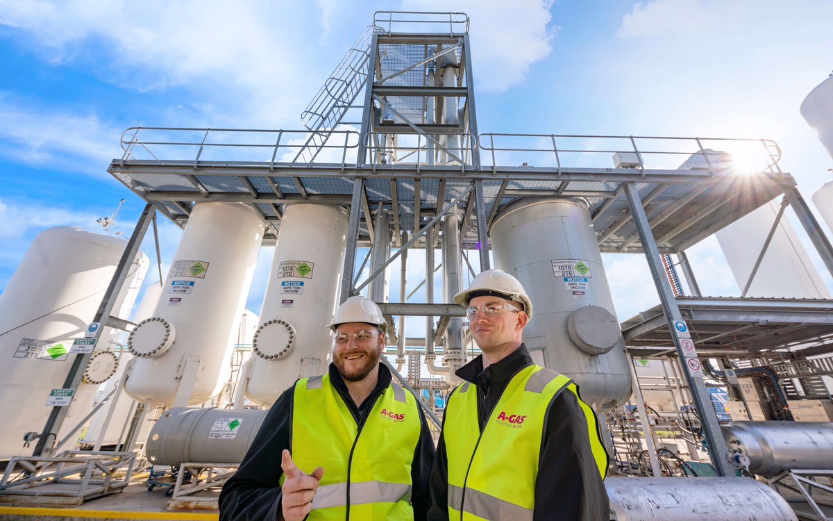 Two men in yellow high-vis jackets talking and smiling in front of white separation towers