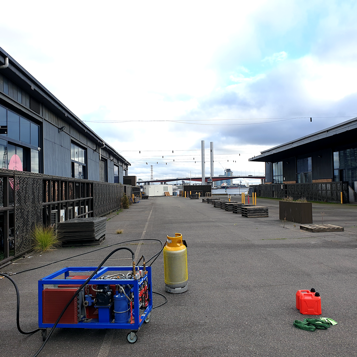 Wide shot of a site with two grey cylinders attached to a blue recovery unit in the foreground