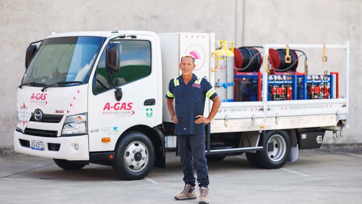 Man standing in front of a white truck with hands on hips while looking at the camera