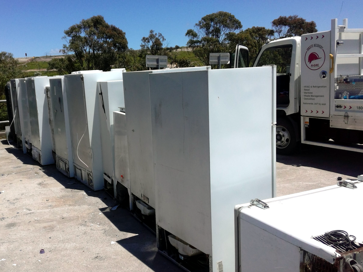 A row of disused fridges from behind in a scrapyard