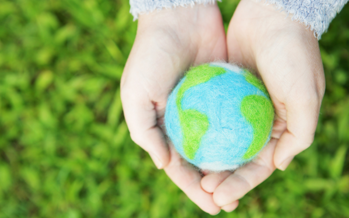 Two hands holding a model of the globe taken from above