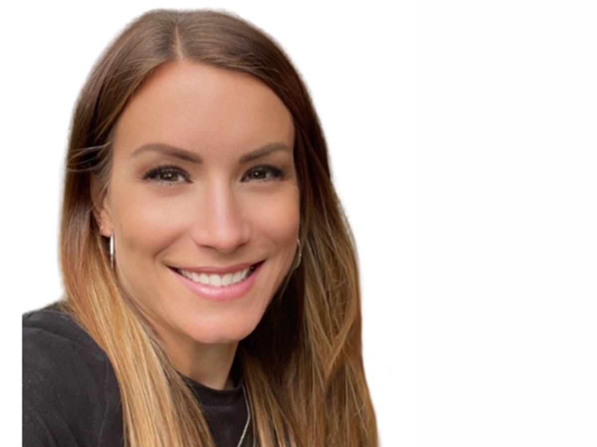 A close-up of a woman with brown hair smiling against a white background