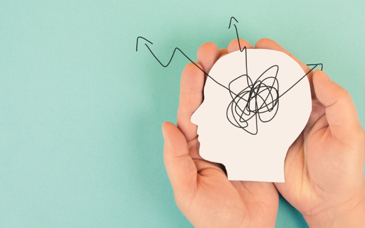 A banner image with human hands holding a white cutout of a head on a light green background
