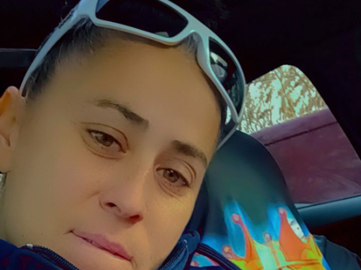 A close-up of a woman sitting in dark blue fleece a car looking at the camera