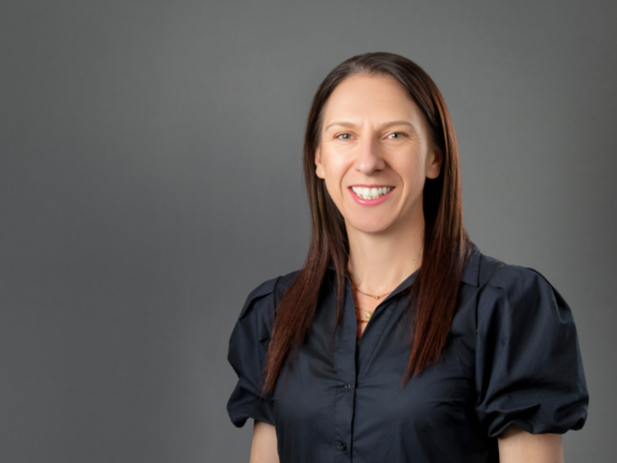 Headshot of a smiling woman against a dark grey backdrop