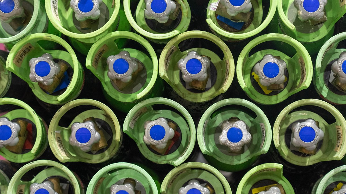 Rows of cylinders with green tops and blue valves from above
