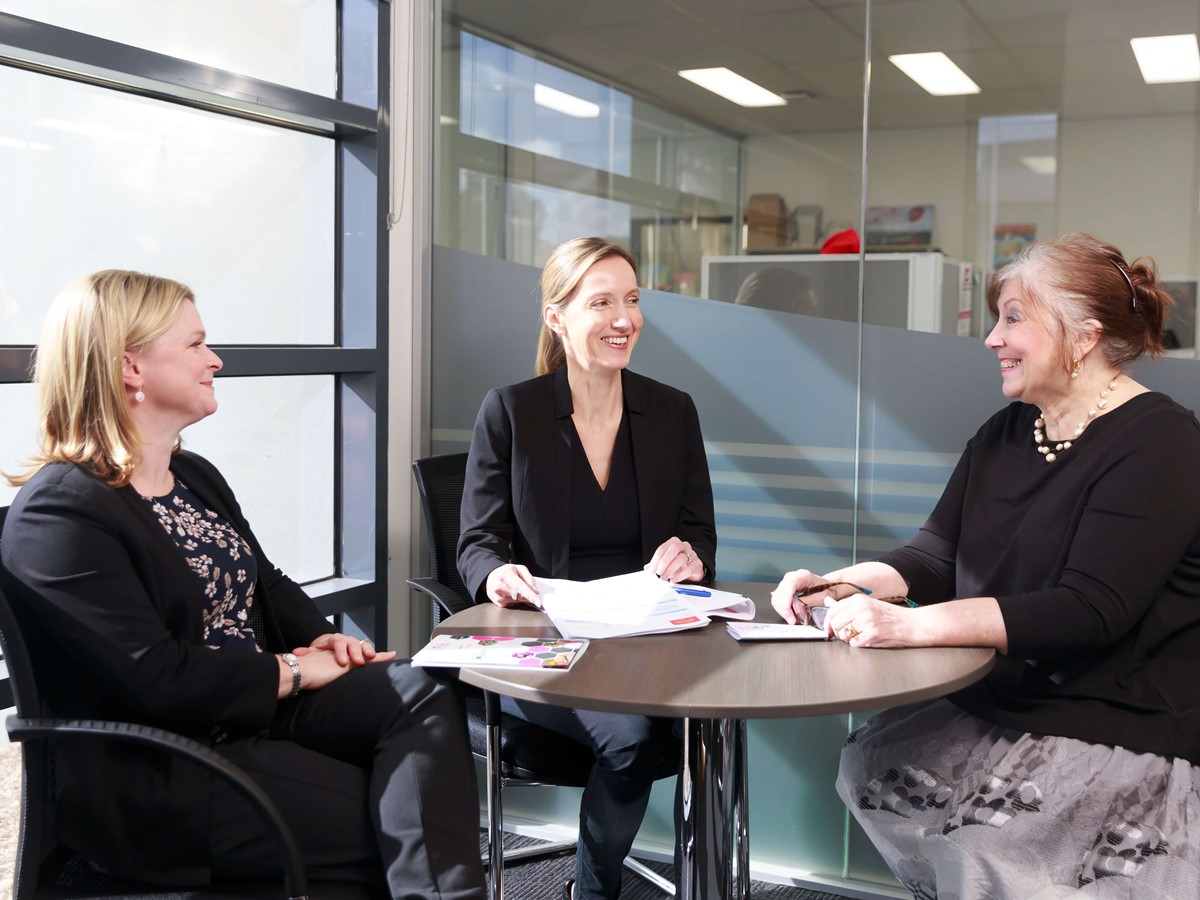 Three women sat around a table in a meeting